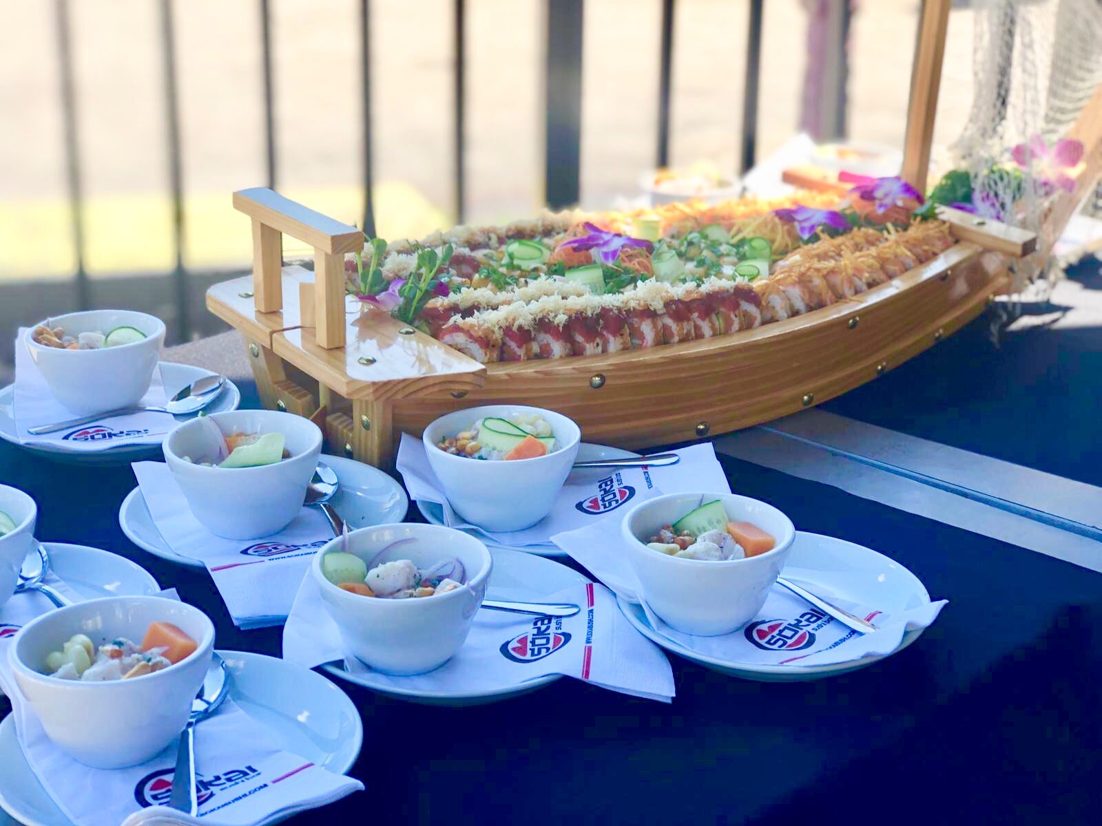 Small bowls of ceviche and a sushi boat on top of a table